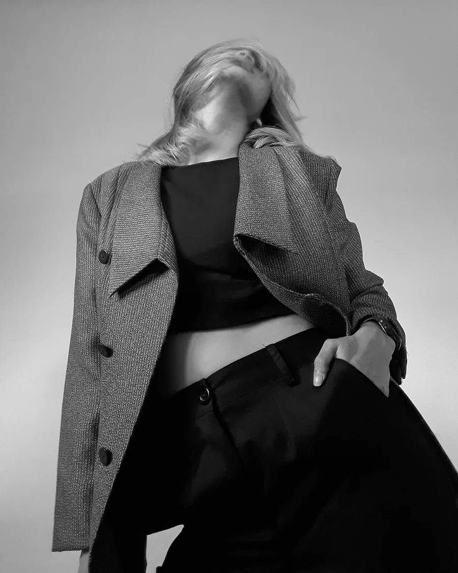 Editorial photograph of a model in a grey coat, hand in pocket